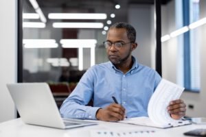 Focused mature African American businessman working in modern office, reviewing documents, and